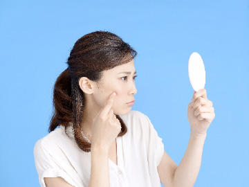 ニキビを鏡でみる女性